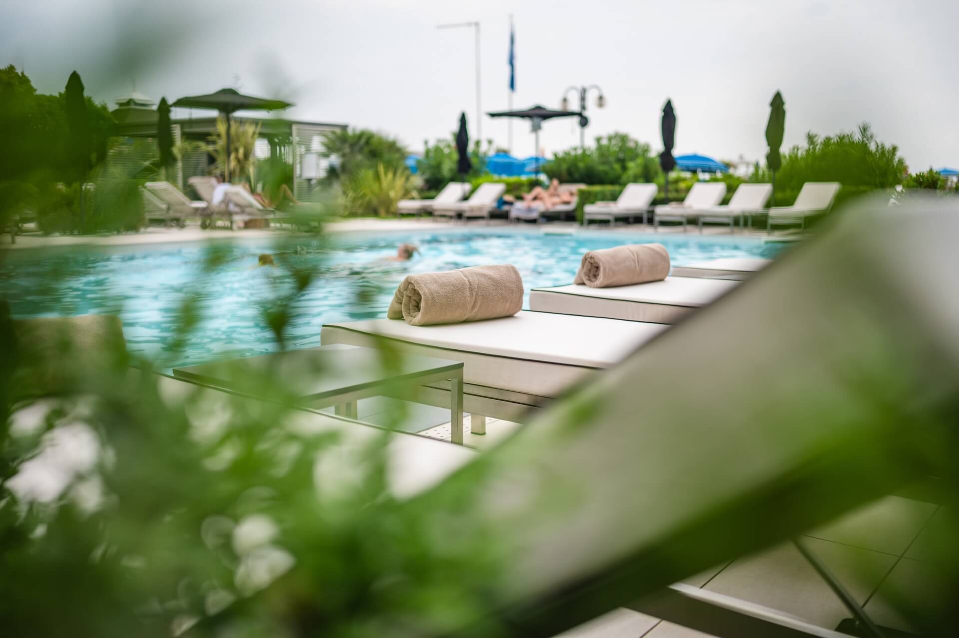 lettini a bordo piscina dotati di asciugamano e tavolino per appoggiare elementi personali