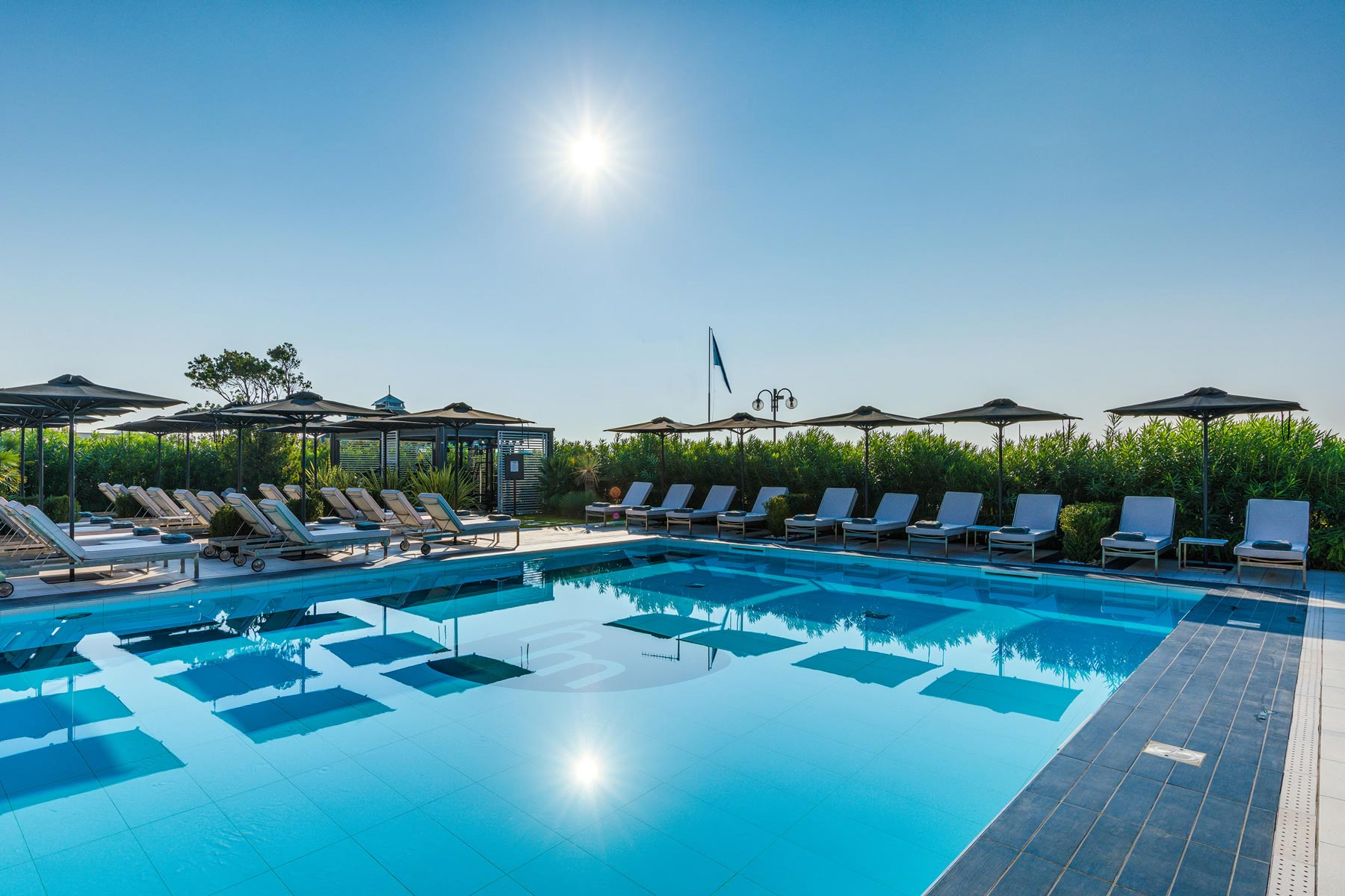 piscina dotata di ombrelloni e lettini con asciugamano